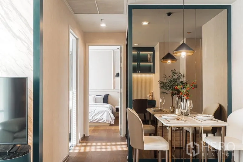 Condominium for rent in Khlong Toei, Bangkok - Master bedroom with tall curtains, twin pendant lights, and paneled headboard wall.