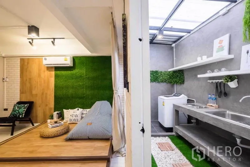 Detached House for rent in Khlong Toei, Bangkok - Lounge opening to a semi-outdoor kitchen with concrete counters and a washing machine.