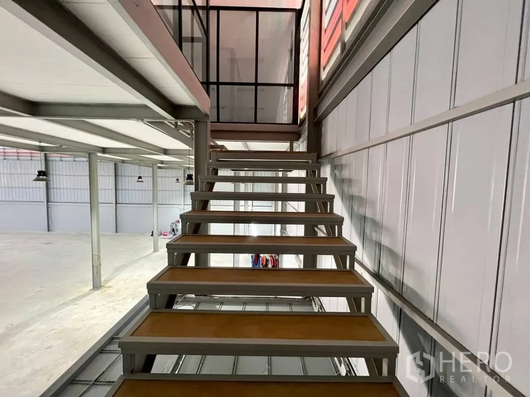 Warehouse for rent in Sai Mai, Bangkok - Metal staircase ascending to the mezzanine level beside ventilated wall panels.