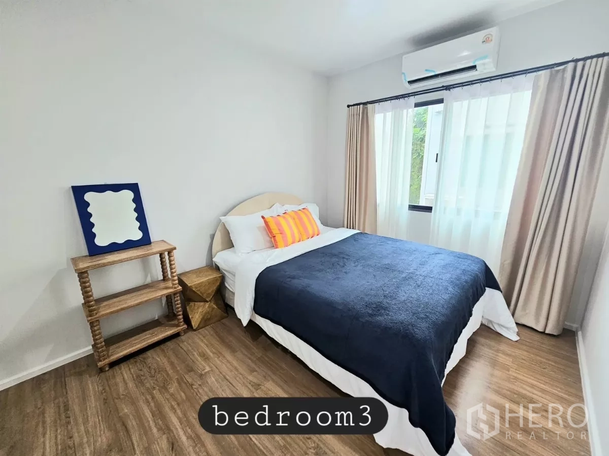 Townhouse for rent in Saphan Sung, Bangkok - Third bedroom with double bed, open shelving and bright curtains.