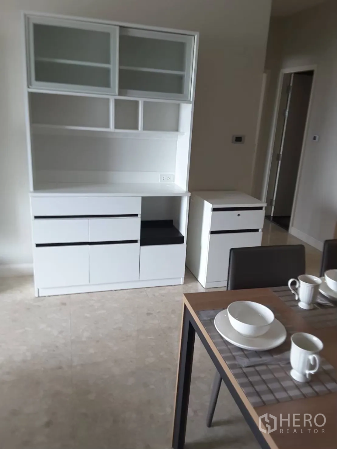 Condominium for rent in Khlong Toei, Bangkok - Dining area with a table set for four and a white storage cabinet.