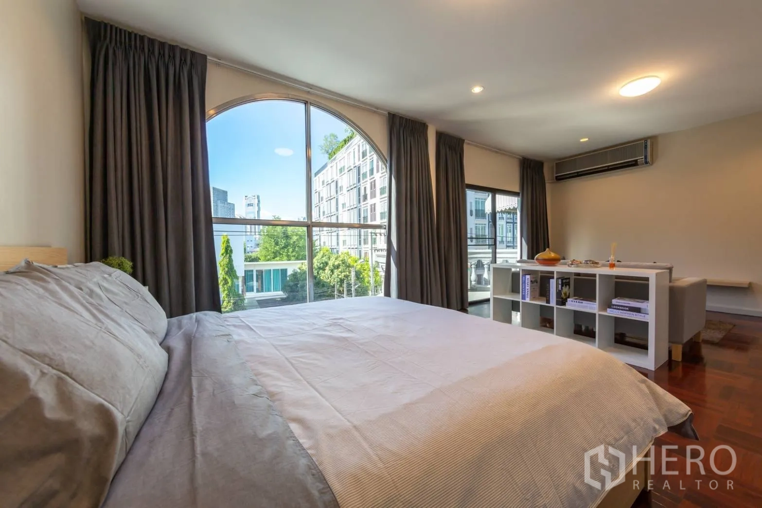 Home Office for rent in Bang Rak, Bangkok - Bedside view toward floor-to-ceiling arched windows with city outlook.