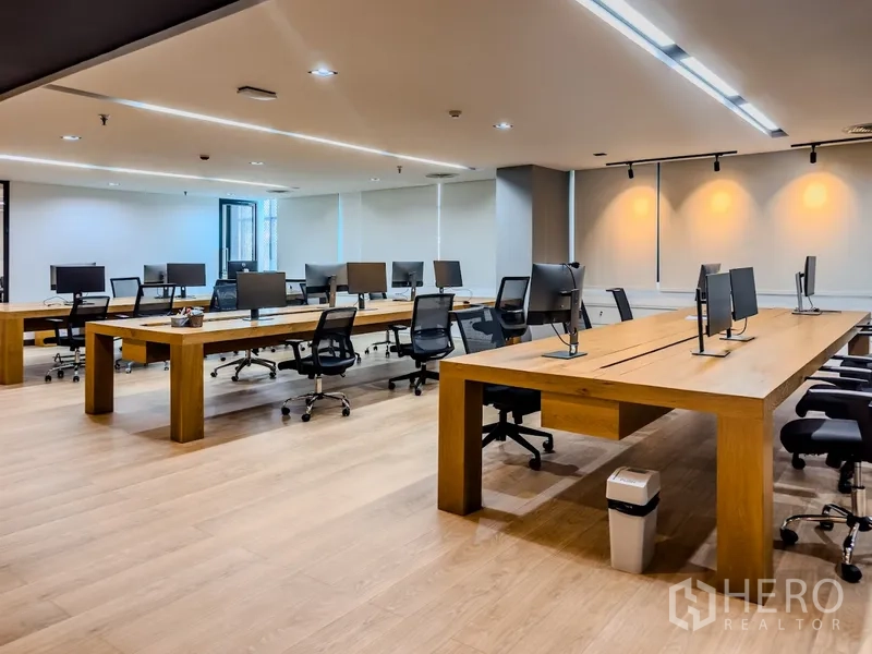 Office Space for rent in Bang Rak, Bangkok - Open-plan office with large wooden desks, task chairs, and ceiling lights.