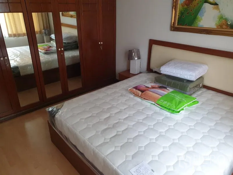 Condominium for rent in Watthana, Bangkok - Master bedroom with a queen bed, upholstered headboard, and mirrored wooden wardrobe.