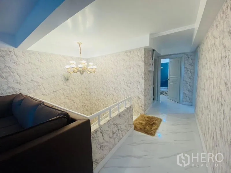 Condominium for rent or sale in Watthana, Bangkok - Upper-floor landing with staircase, chandelier and a cozy seating nook.
