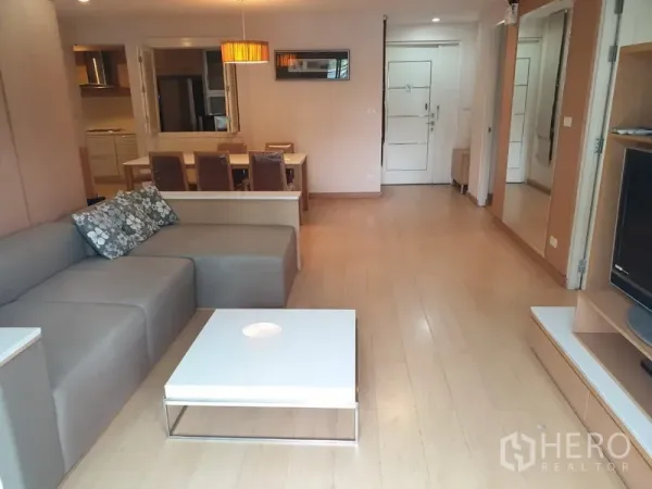 Condominium for rent in Watthana, Bangkok - Open-plan living and dining area with light wood floors, sofa set, and dining table.