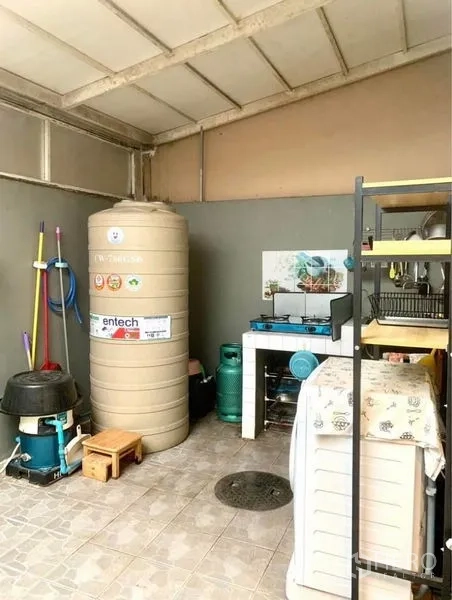 Townhouse for rent in Suan Luang, Bangkok - Covered utility area with water tank, gas cooktop and storage shelves.