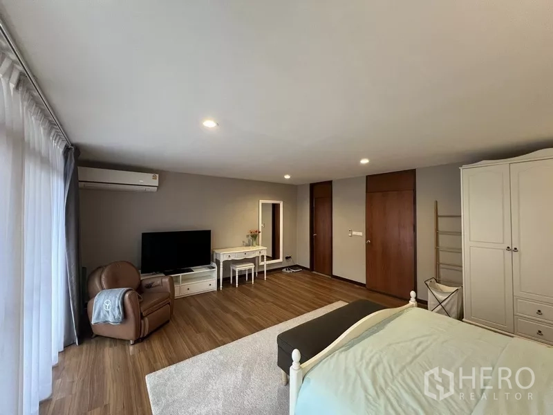 Townhouse for rent or sale in Suan Luang, Bangkok - Master bedroom angle showing TV console, vanity table and double doors.
