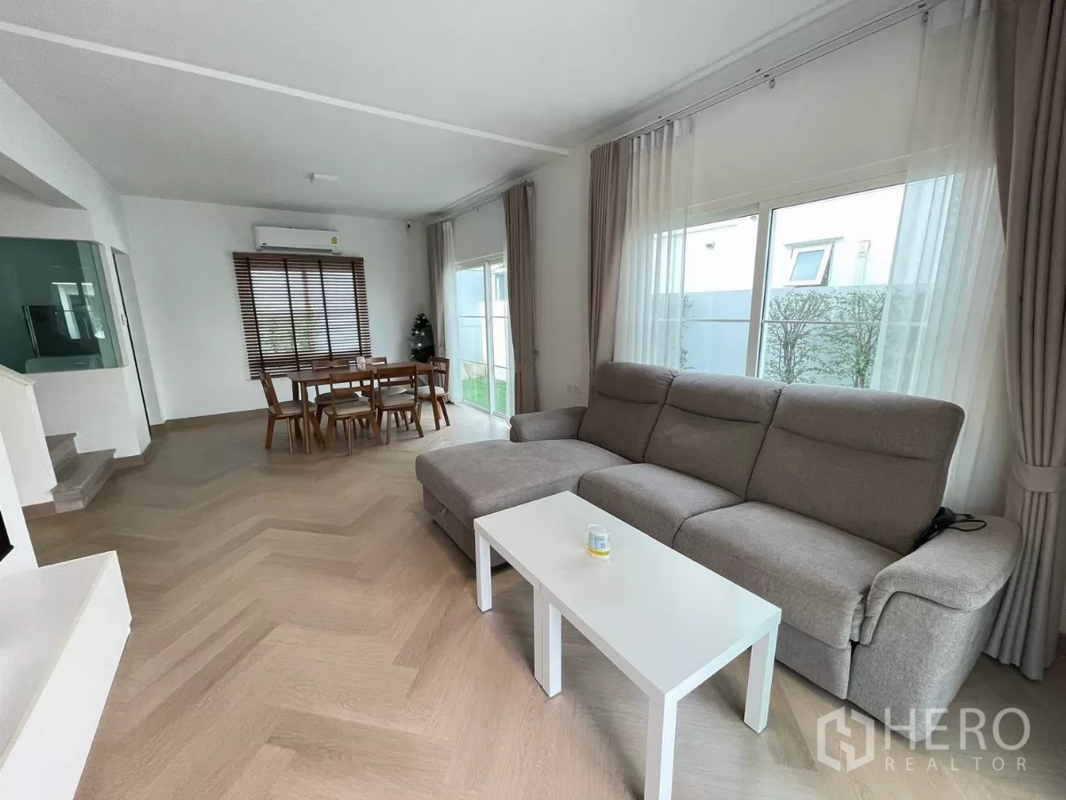 บ้าน ให้เช่าหรือขายในBang Phli, Samut Prakan - ห้องนั่งเล่นและรับประทานอาหารแบบโอเพ่นแปลนครบชุด โซฟา L หน้าต่างบานใหญ่ และพื้นไม้ลายก้างปลา