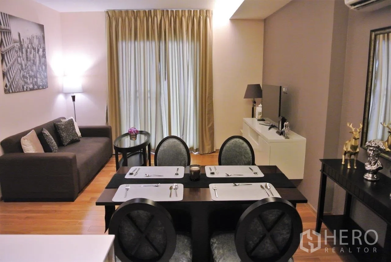 Condominium for rent in Watthana, Bangkok - Open-plan living and dining area with sofa, four-seat table, TV console and floor-to-ceiling curtains on wood flooring.