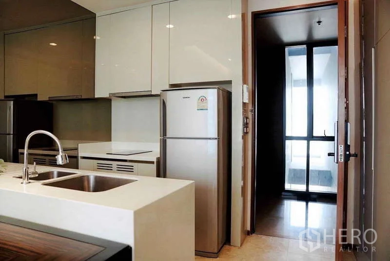 Condominium for rent or sale - Compact kitchen with stone countertop, sink and stainless refrigerator.