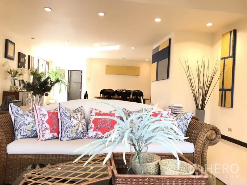 Detached House for rent in Phra Khanong, Bangkok - Open-plan living and dining room with wicker sofa, indoor plants, and modern wall art.