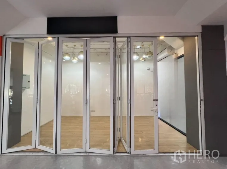 Retail Space for rent in Pathum Wan, Bangkok - Front view of retail shop with full-height bi-fold glass doors and warm wood flooring ready for signage.