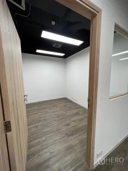 Office Space for rent in Khlong Toei, Bangkok - Compact private office room with wood-look flooring and dark exposed ceiling.