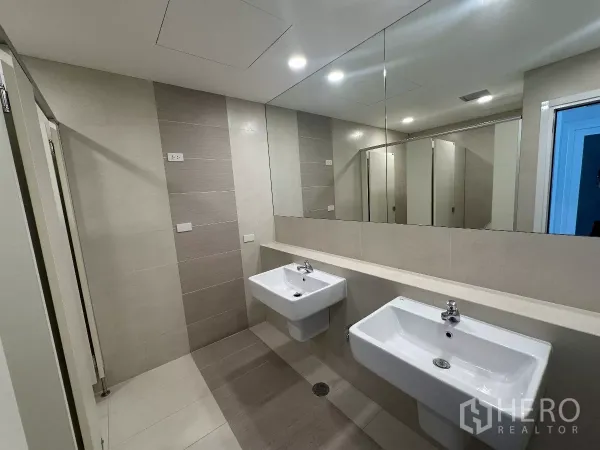办公空间 出租在Watthana, Bangkok - 现代化洗手间，双壁挂洗手盆、大镜面与中性色瓷砖，设有隔间。