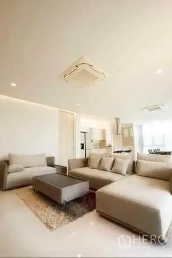 Townhouse for rent in Huai Khwang, Bangkok - Spacious lounge with sectional sofa and rug connected to an open kitchen and dining zone.