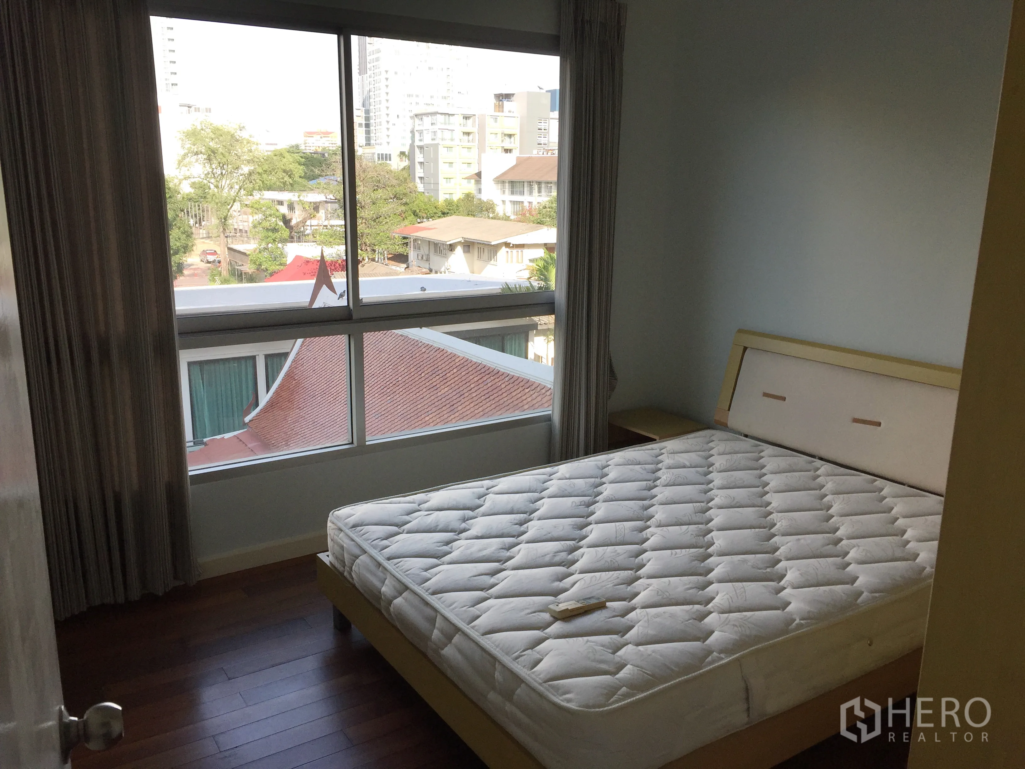 Condominium for rent in Watthana, Bangkok - Cozy bedroom with large window and neighborhood city view over Thonglor.
