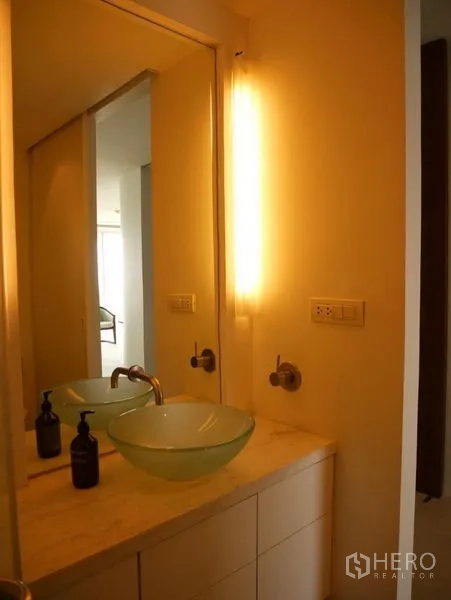 Condominium for rent in Khlong Toei, Bangkok - Vanity with vessel sink, backlit mirror and marble countertop.