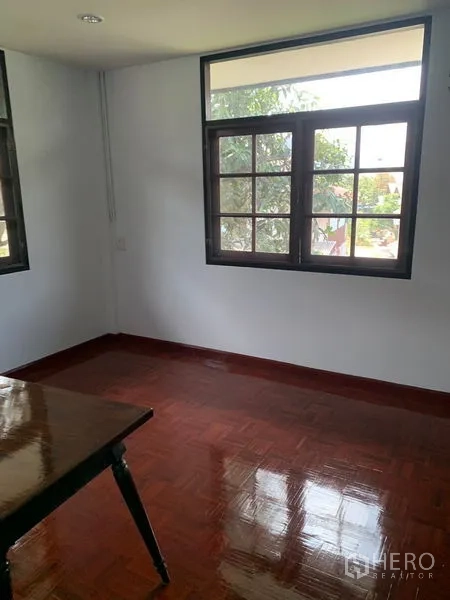 Detached House for rent in Khlong Toei, Bangkok - Upper-floor room with polished wood floor and a corner table by the windows.
