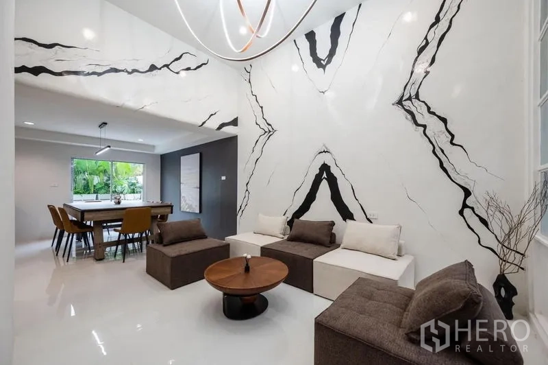 Townhouse for sale - Double-height living room with dramatic marble feature wall and modern sofa set.