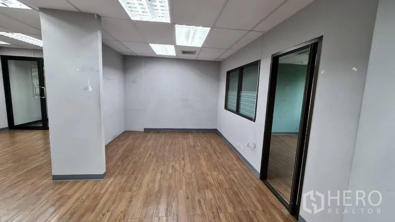 办公空间 出租在Watthana, Bangkok - 走廊视角，柱体空间通向明亮办公区。