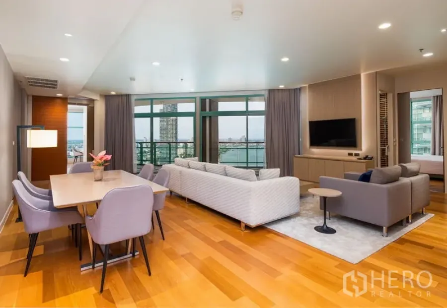 Condominium for rent in Bang Kho Laem, Bangkok - Spacious living and dining area with full‑height windows and a river‑view balcony.