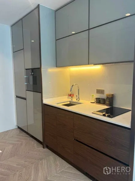 Condominium for rent in Khlong Toei, Bangkok - Sleek built-in kitchen with induction hob, sink, and under-cabinet lighting.