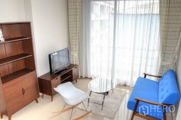 Condominium for rent in Phaya Thai, Bangkok - Another view of the bright living area with blue sofa and balcony curtains.