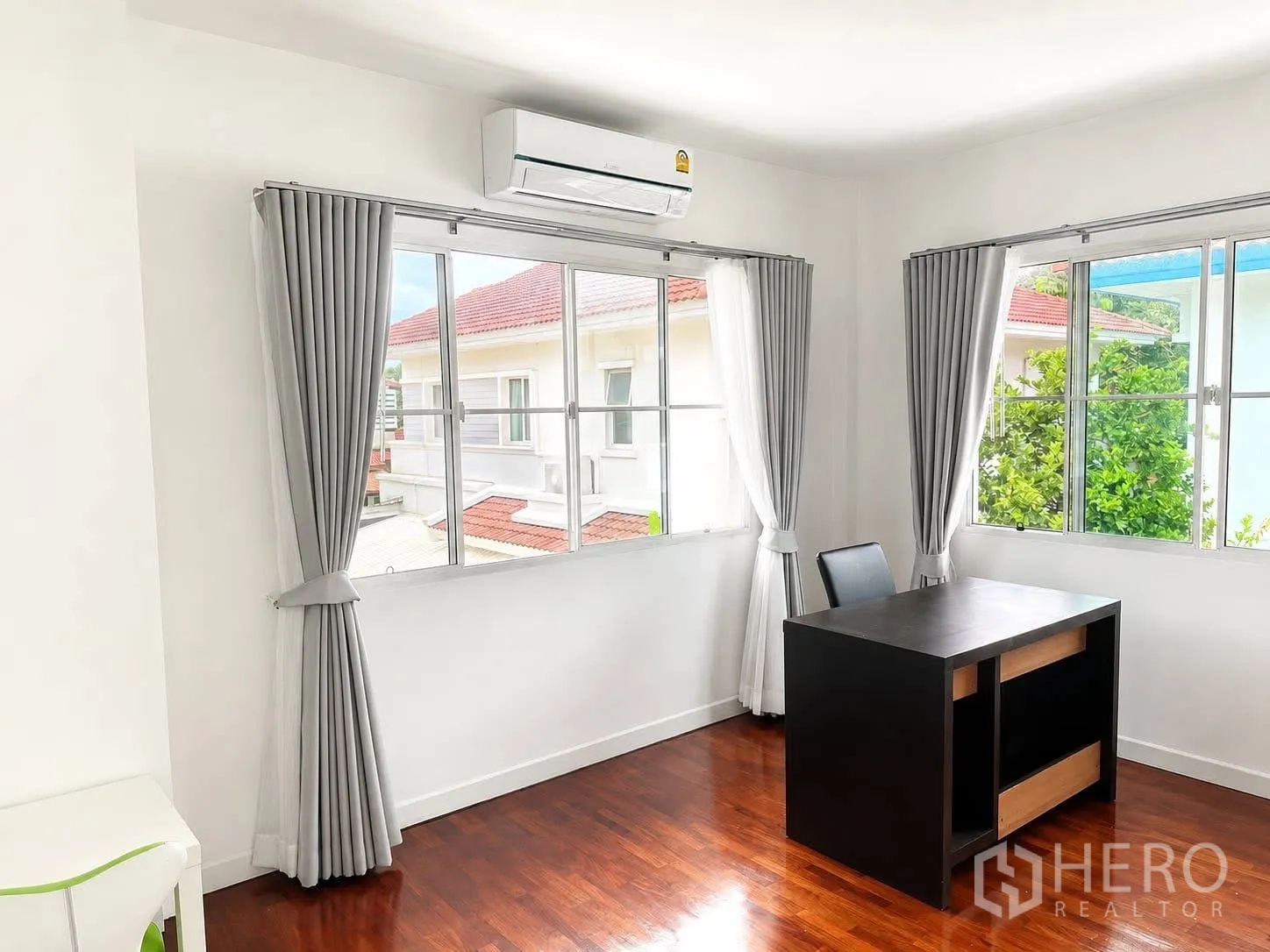 独栋房屋 for rent in Prawet, Bangkok - 明亮的书房角落，设大窗、灰色窗帘、空调与黑色书桌，木地板。