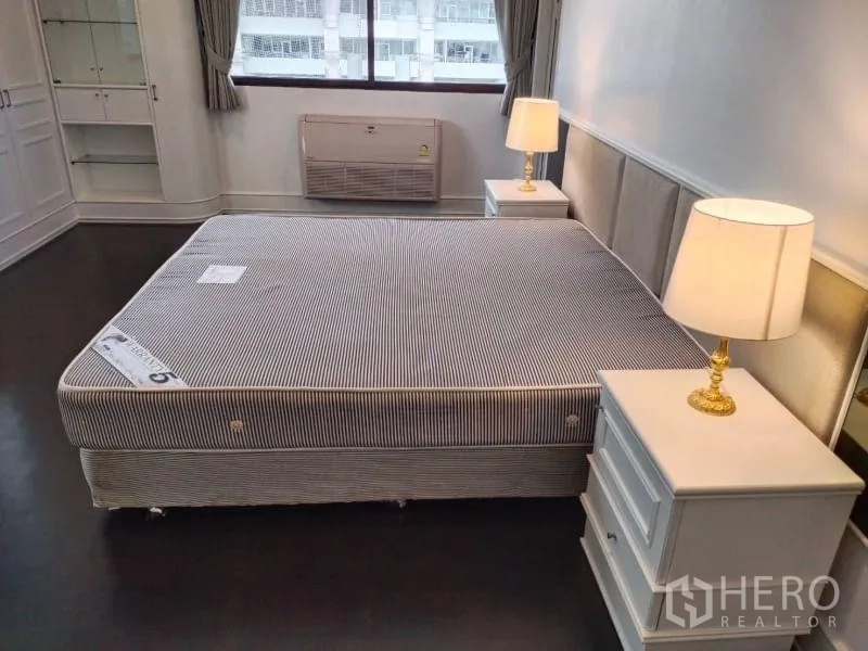 Condominium for rent in Sathon, Bangkok - Primary bedroom with king-size bed, matching nightstands and lamps, and a large window.