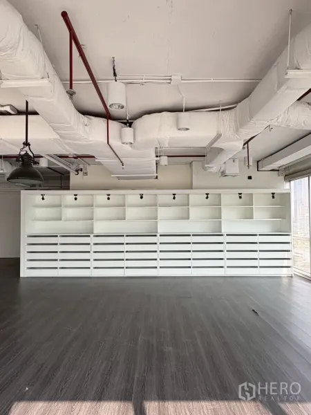 Office Space for rent in Khlong Toei, Bangkok - Built-in white shelving and storage spanning one wall.