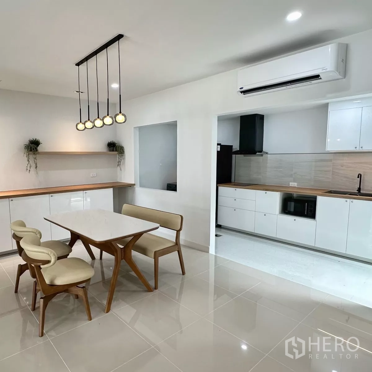 联排别墅 出租在Bang Phli, Samut Prakan - 吊灯上方的用餐区，望向白色一字形厨房与台面。