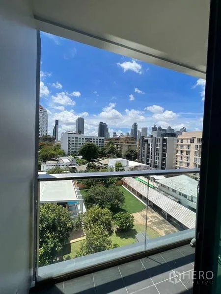 公寓 出租或出售在Watthana, Bangkok - 阳台透明栏杆，可俯瞰绿地与曼谷天际线。