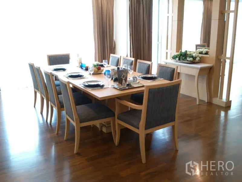 Condominium for rent in Khlong Toei, Bangkok - Dining area close-up showing long table, cushioned chairs and a decorative console.
