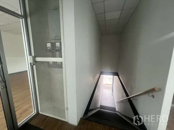 Retail Space for rent - Stairwell with handrail leading up to the retail floor and glass entry door.