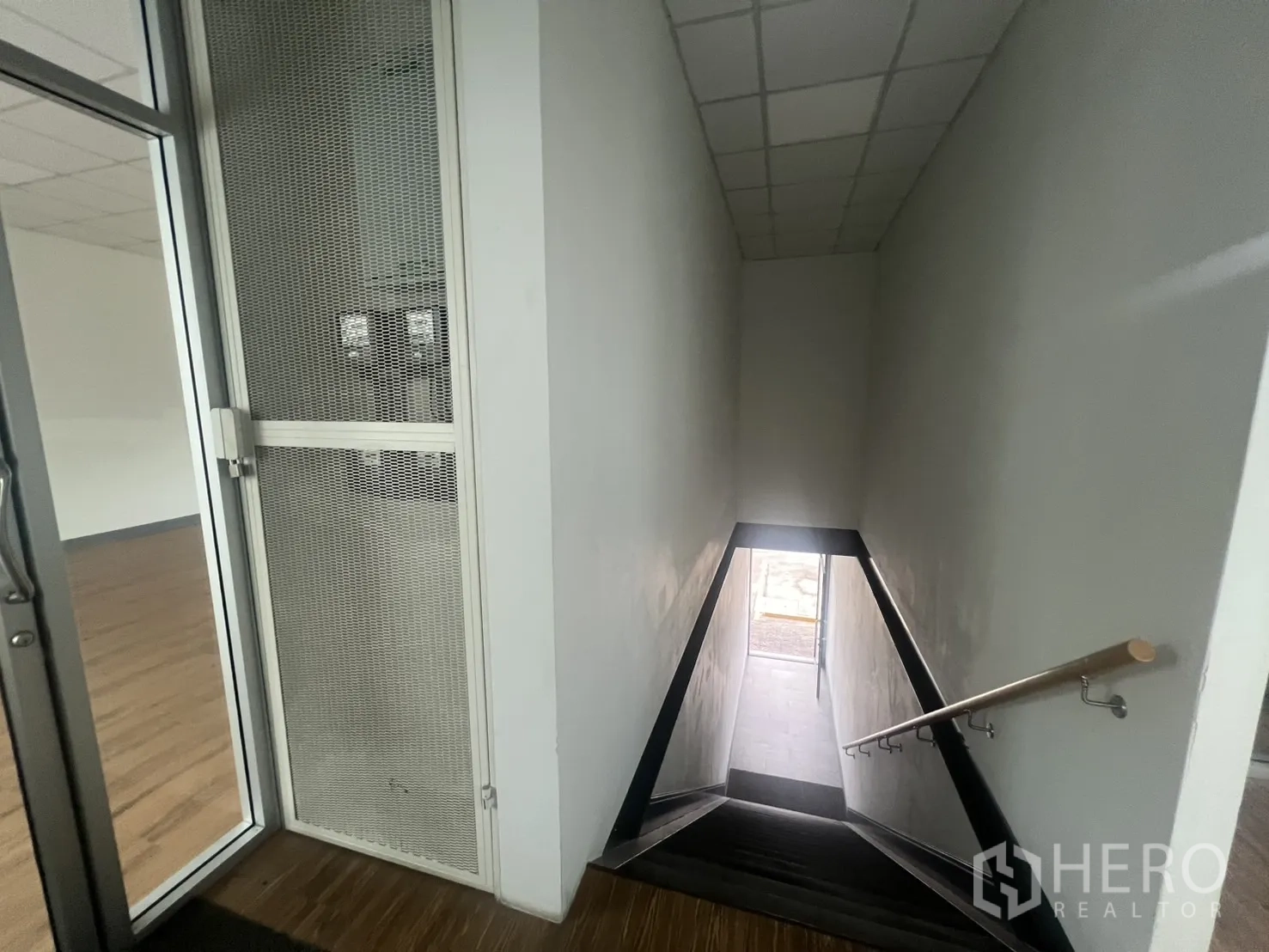 Retail Space for rent - Stairwell with handrail leading up to the retail floor and glass entry door.