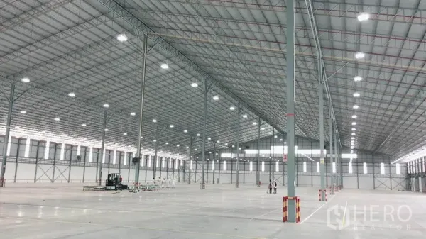 Warehouse for rent in Si Racha, Chon Buri - Spacious warehouse interior with high steel truss roof, bright lighting and polished concrete floor.