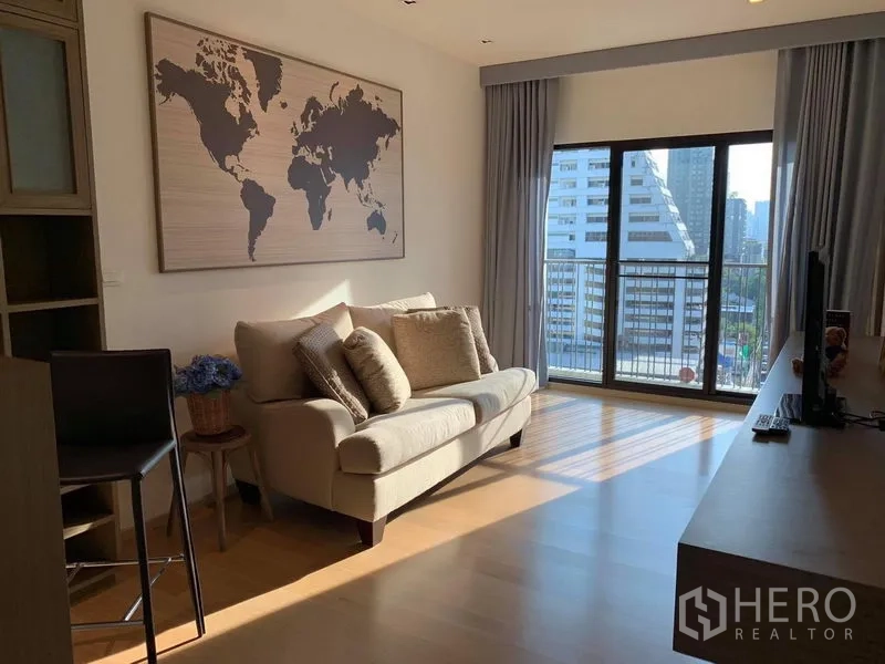 Condominium for rent in Phaya Thai, Bangkok - Sunlit lounge area with cream sofa, large window drapes, and balcony facing skyline.