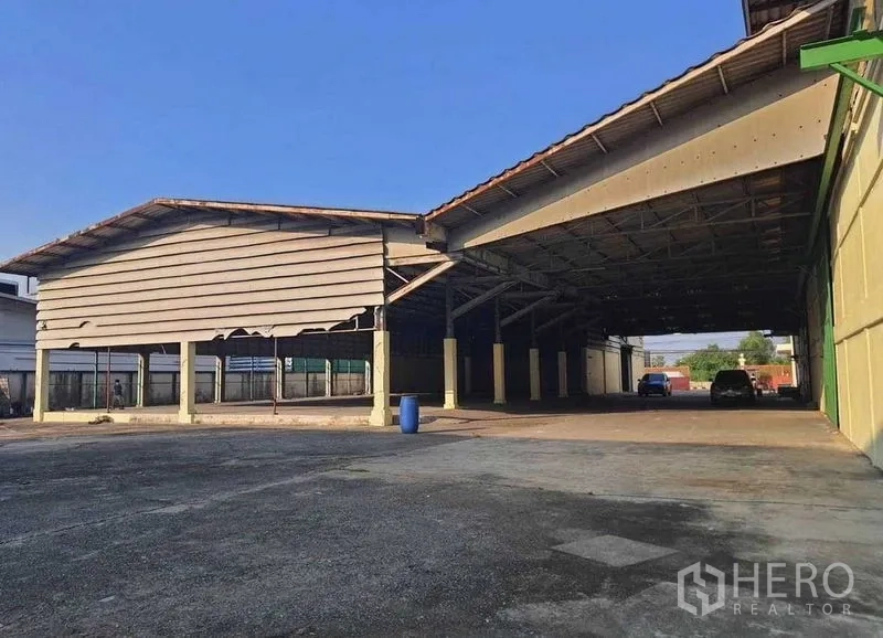 Warehouse for rent or sale in Mueang Pathum Thani, Pathum Thani - Covered loading bays and a drive-through area next to the warehouse structures.