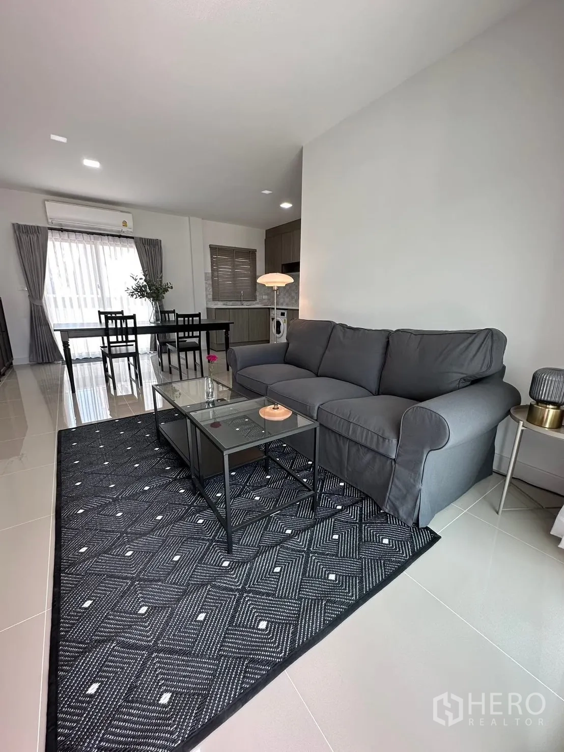 联排别墅 for rent in Bang Phli, Samut Prakan - 开放式客厅，灰色沙发、玻璃茶几和用餐区。