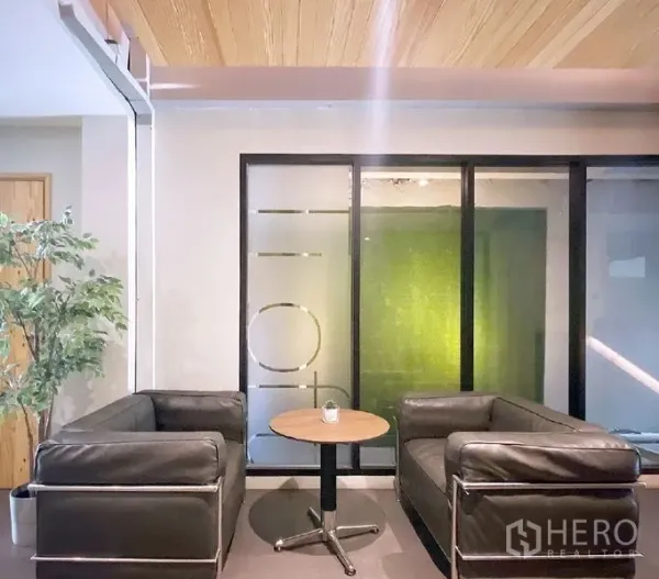 Office Space for rent in Bang Rak, Bangkok - Cozy lobby with two black leather sofas, a round coffee table, and a frosted glass partition in a Bang Rak office.