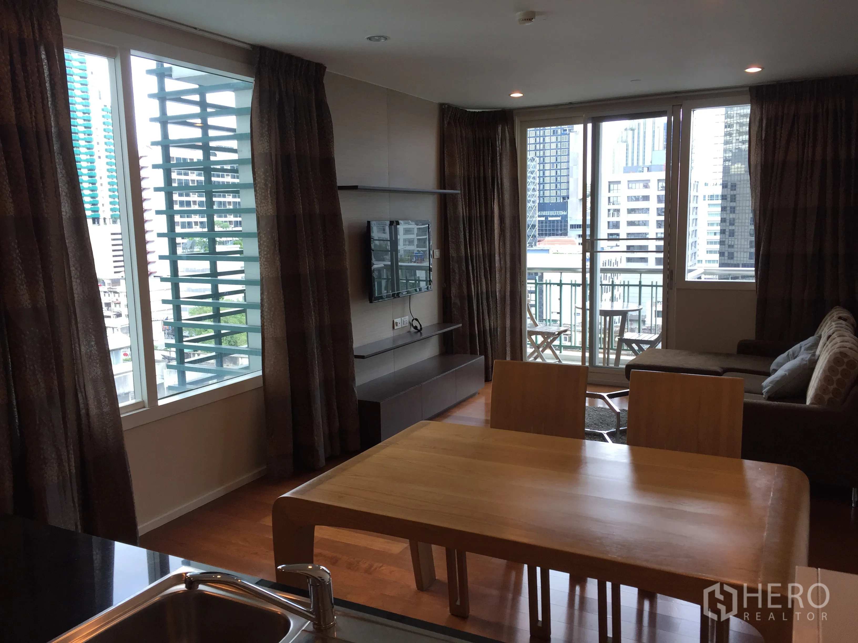 公寓 出租或出售在Watthana, Bangkok - 采光良好的客厅，挂墙电视与转角沙发，阳台俯瞰曼谷天际线