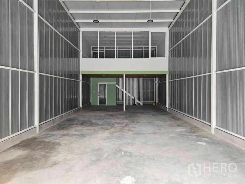 Warehouse for rent in Prawet, Bangkok - High-bay warehouse interior in Prawet with a mezzanine glass office and staircase.