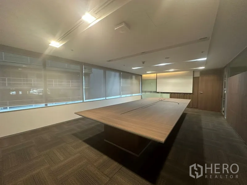 Office Space for rent in Khlong Toei, Bangkok - Modern boardroom featuring a large wooden conference table, carpet flooring, and roller blinds.