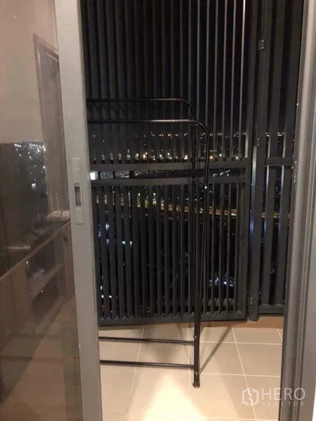 Condominium for rent in Khlong Toei, Bangkok - Covered balcony with metal louver panels overlooking the Bangkok night skyline.