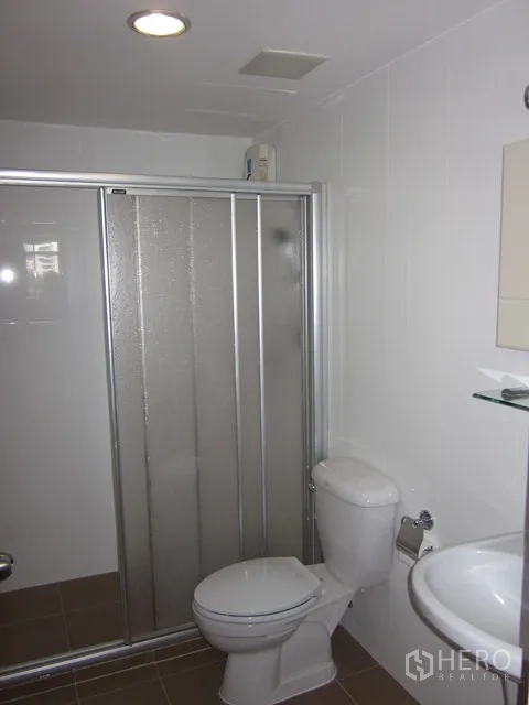Condominium for rent or sale in Watthana, Bangkok - Bathroom with glass-enclosed shower, toilet, and pedestal sink.