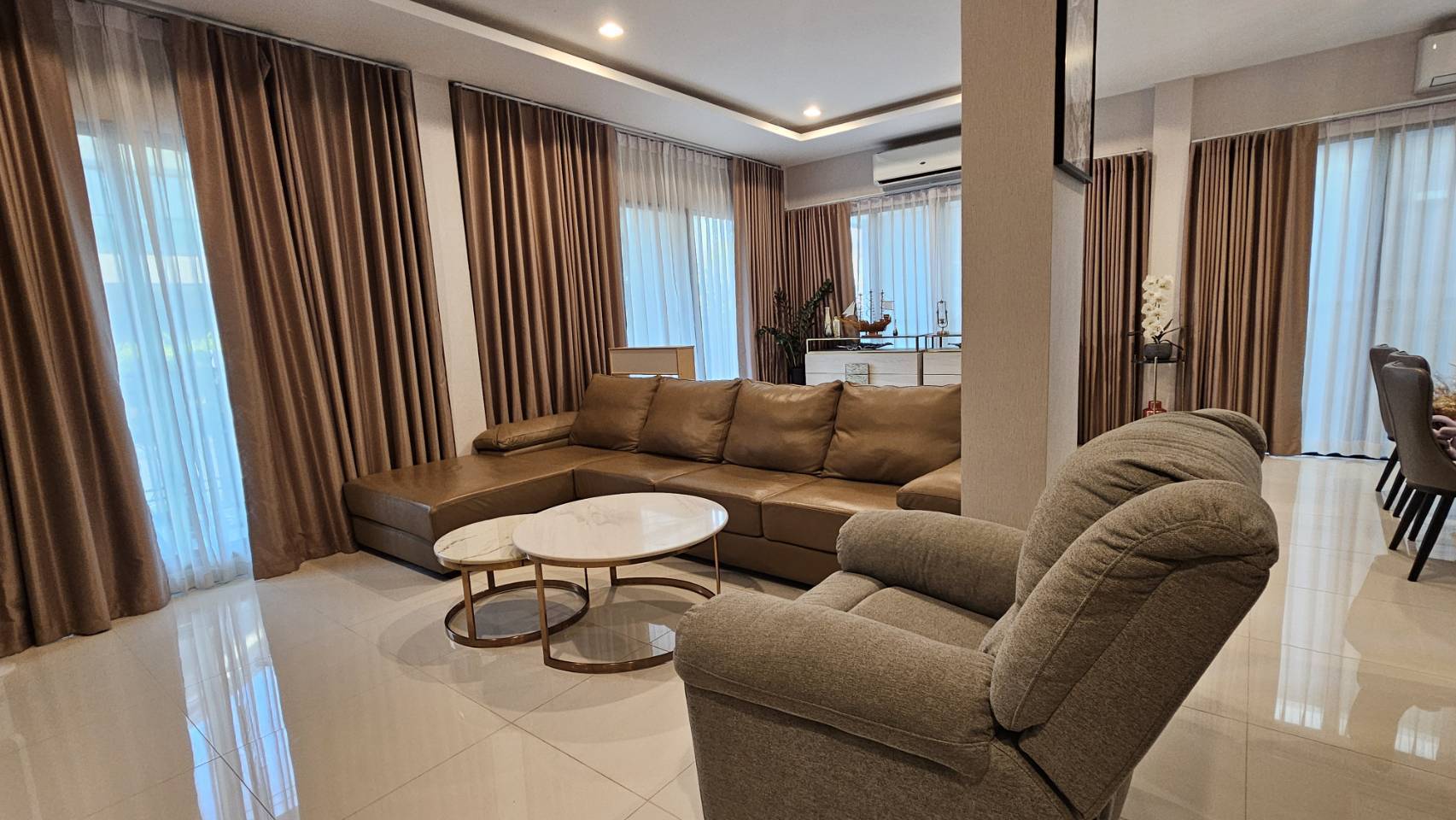 Detached House for rent in Saphan Sung, Bangkok - Corner lounge with brown sectional, armchair and round coffee tables.
