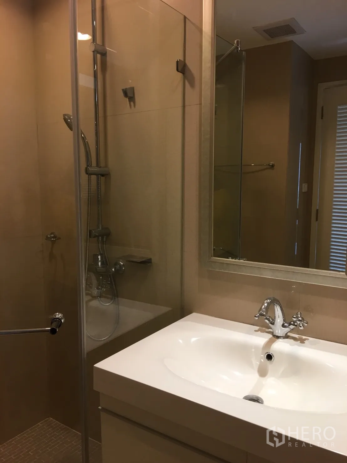 Condominium for rent in Watthana, Bangkok - Modern bathroom with glass-enclosed shower and vanity sink.