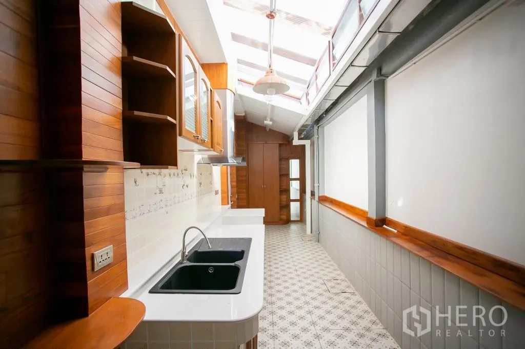 独栋房屋 for rent or sale in Huai Khwang, Bangkok - 采光天窗的长廊式厨房，白色台面与双黑色水槽。