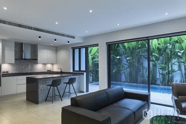 Townhouse for sale in Watthana, Bangkok - Kitchen and living area with sliding doors opening to a blue-tiled pool and deck.